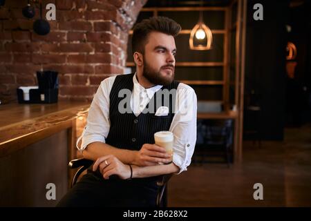 Junger, nachdenklicher Casino-Mitarbeiter, der sich auf dem Stuhl ausruhen kann, Nahaufnahme des Fotos. Stockfoto