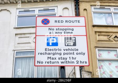 Schild mit Parkbeschränkungen an der Ladestelle für Elektrofahrzeuge an einer Bordseite im Süden Londons. Stockfoto