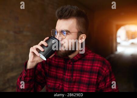 Hübsche junge bärtige Männer in stilvollem Karomuster, die Kaffee in einer Tasse zum Mitnehmen trinken, Freizeit, Freizeit, Lifestyle, Nahaufnahme. Stockfoto