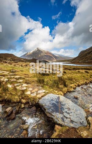 Stepping Stones über Schmelzwasser von schneebedecktem Glyder Fawr, das nach Llyn Idwal führt, mit Pen yr Ole Wen im Hintergrund, Snowdonia, Nordwales Stockfoto