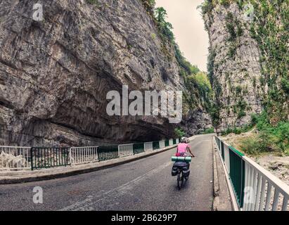 Radtourist, der Reisende fährt auf der Asphaltstraße zwischen den Felsen in der Schlucht Stockfoto