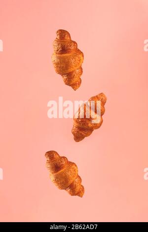 Croissants auf pinkfarbenem Hintergrund. Levitationsszene. Stockfoto