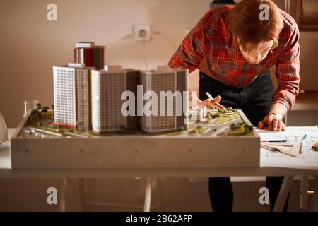 Junger, professionell talentierter Architekt, der seine Messungen auf dem Papier schreibt, Nahaufnahme, Interesse, Lebensstil und Konzentration Stockfoto