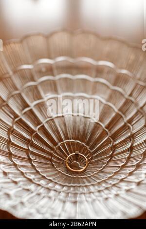 Hochzeit in einem schönen Glas. Goldener Ring mit Diamant in einer Glasschale aus Spitze. Selektiver Fokus. Stockfoto