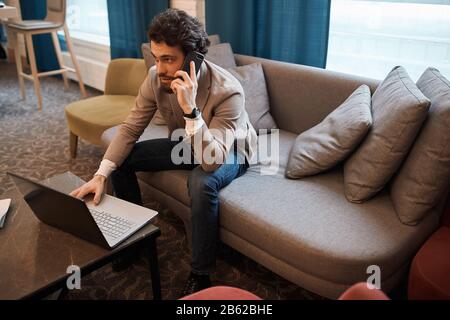 Junger Mann in legerer Mode, der ein Gespräch mit Kunden, Kunden führt. Draufsicht. Techologie, Mann verdient Morney, Einkauf onlin Stockfoto