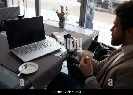 Junger Geschäftsmann, der einen Telefonanruf mit dem Gerät führt, um sich mit dem Netz zu verbinden, Nahaufnahme Foto. Mann, der online einkaufen geht. Nahansicht Foto Stockfoto