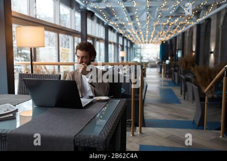 Attraktiver Kerl, der beim Tischen im Café Tee trinkt, Nahaufnahme. Kopieren sie sp[ace.interets, Hobby Stockfoto