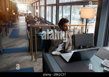 Junger Geschäftsmann, der Frühstück serviert, sich entspannen, Kaffee schmeckt. Nahaufnahme Stockfoto