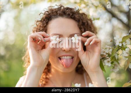 Junges attraktives Mädchen Spaziergänge in Spring Green Park genießen Sie blühende Natur. Gesunde lächelnde Mädchen auf der Feder Rasen drehen. Allergie ohne. Stockfoto