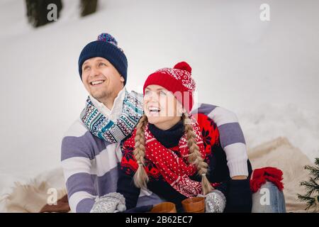 Junge Paare in warmen Pullovern im Winter blicken auf den Himmel. Stockfoto