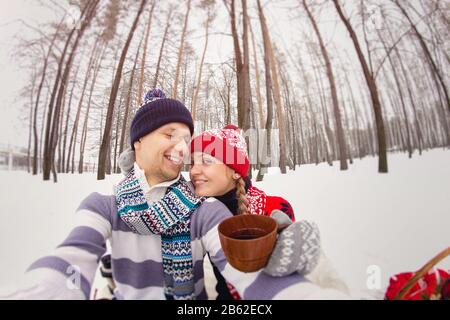 Ein Paar gießt Tee im Becher aus Thermoskannen im Winter Park. Nahaufnahme. Stockfoto