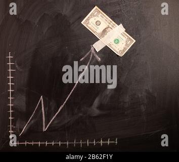 Auf dem Schwarzen Brett gezeichnete Wachstumskarte des Dollars. Investitionskonzepte und Interessen Unternehmenswachstum. Steigende Grafik aus Dollars. Stockfoto