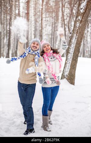 Schneeballkampf. Das Winterpaar hat Spaß, im Schnee draußen zu spielen. Junges freudiges Paar verliebt sich Stockfoto
