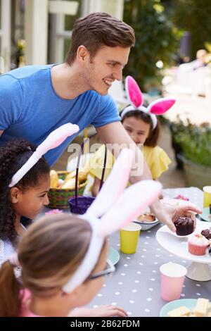 Vater Mit Kindern, Die Hase Ohren Tragen Und Die Osterparty Im Freien Im Garten Zu Hause Genießen Stockfoto