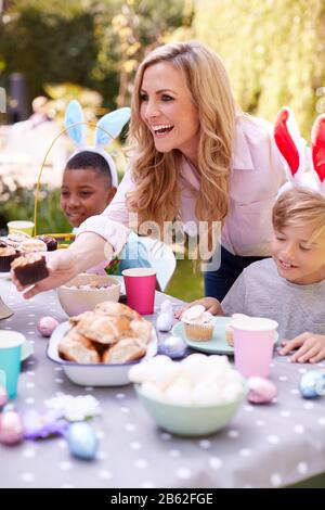 Mutter Mit Kindern, Die Hase Ohren Tragen Und Die Osterparty Im Freien Im Garten Zu Hause Genießen Stockfoto