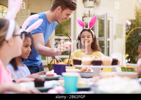 Vater Mit Kindern, Die Hase Ohren Tragen Und Die Osterparty Im Freien Im Garten Zu Hause Genießen Stockfoto