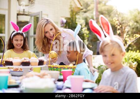 Mutter Mit Kindern, Die Hase Ohren Tragen Und Die Osterparty Im Freien Im Garten Zu Hause Genießen Stockfoto
