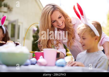 Mutter Mit Kindern, Die Hase Ohren Tragen Und Die Osterparty Im Freien Im Garten Zu Hause Genießen Stockfoto