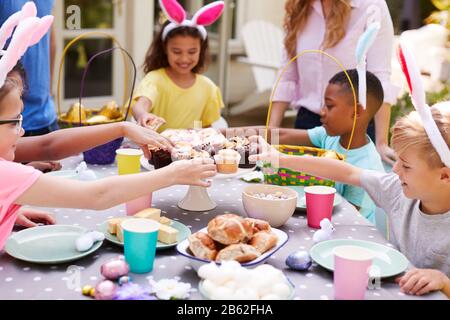 Eltern Mit Kindern, Die Hasen Tragen, Genießen Die Osterparty Im Freien Im Garten Zu Hause Stockfoto