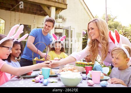 Eltern Mit Kindern, Die Hasen Tragen, Genießen Die Osterparty Im Freien Im Garten Zu Hause Stockfoto