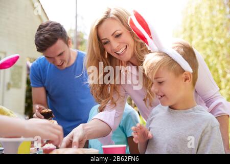 Eltern Mit Kindern, Die Hasen Tragen, Genießen Die Osterparty Im Freien Im Garten Zu Hause Stockfoto