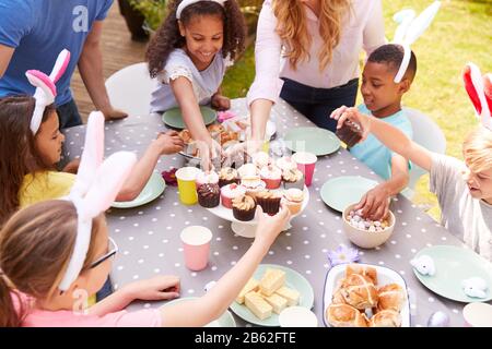 Eltern Mit Kindern, Die Hasen Tragen, Genießen Die Osterparty Im Freien Im Garten Zu Hause Stockfoto