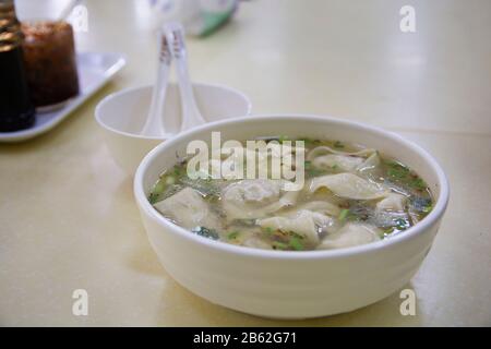 Nahaufnahme einer traditionellen chinesischen Knödel Suppe, mit Schalotte, in einer weißen Schüssel Stockfoto