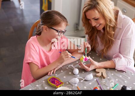 Mutter Mit Tochter Sitzt Am Tisch Und Schmückt Eier Für Ostern Zu Hause Stockfoto