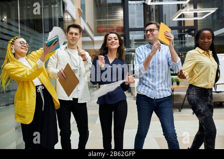 Lustige, glückliche Büroangestellte werfen Dokumente, Papier, feiern Erfolg, Sieg, Spaß im Freien Stockfoto