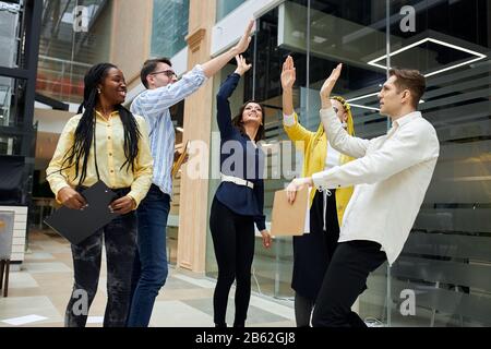 Fröhliches, ehrfürchtiges Team, das sich fünf Personen übergibt, den Sieg feiert, gewinnt, gute Arbeit, gut gemacht Stockfoto