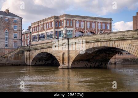 Die Ouse Bridge in York. Die 19. Steinstruktur überspannt den Fluss Ouse und Ziegelbauten befinden sich auf jeder Seite. Ein Himmel mit Wolken ist oben. Stockfoto