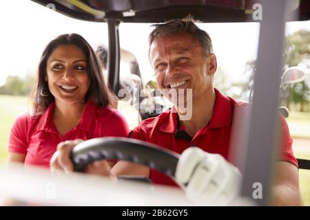 Reifere Paare, Die Golf Spielen Und Buggy Auf Dem Kurs Nach Grün Am Red Letter Day Fahren Stockfoto