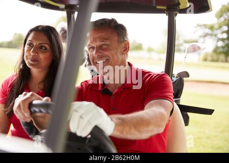 Reifere Paare, Die Golf Spielen Und Buggy Auf Dem Kurs Nach Grün Am Red Letter Day Fahren Stockfoto