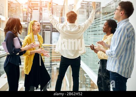 Glückliches junges Team, das ihrem Chef applaudiert, weil er einen erfolgreichen Vertrag abgeschlossen hat, Deal. Stockfoto
