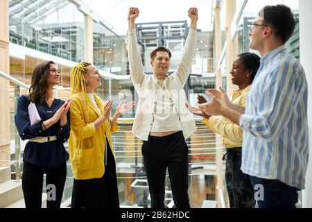 Glücklicher Business man steht mit erhobenen Armen und geklatschten Fäusten, die Erfolg haben. Nahaufnahme. Stockfoto