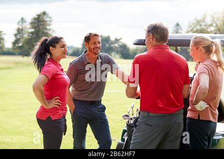 Gruppe Von Männlichen Und Weiblichen Golfspielern, Die Von Golf Buggy Auf Dem Kurs Stehen Stockfoto