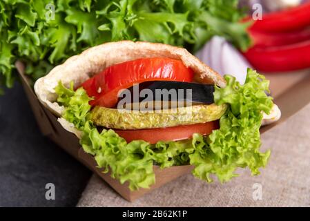 Vegane Döner Kebab Pita mit grünem Salat, gegrillte Tomaten, Eierpflanze, Zucchini in der Lunchbox auf grünem Salat Hintergrund Stockfoto