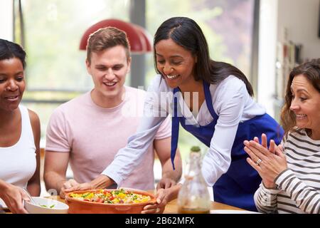 Eine Gruppe Von Freunden, Die Zusammen Zu Hause Um Das Essen Am Tisch Sitzen Stockfoto