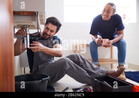 Klempner Für Männer, Der Weiblichen Lehrlinge Beigebracht Hat, Um Auslaufenden Sink Im Badezimmer Zu Fixieren Stockfoto