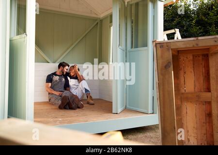 Ein Paar, Das Eine Pause Vom Gebäude Outdoor Summerhouse In Garden nimmt Stockfoto