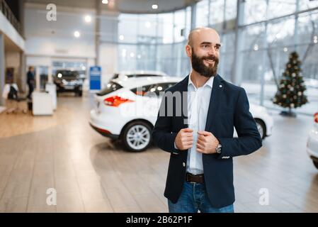 Lächelnder Mann posiert im Autohaus Stockfoto