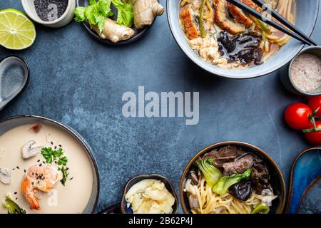 Satz serviert asiatische Suppen auf dunkelblauem Hintergrund der Ansicht von oben. Tom Yum Suppe, Aal Fischsuppe und Ramen Noodle Soup Stockfoto