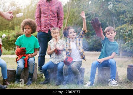 Teamleiter Mit Einer Gruppe Von Kindern Auf Einem Ausflug Zur Außenaktivität Zum Toasten Von Marshmallows Über Dem Lagerfeuer Stockfoto