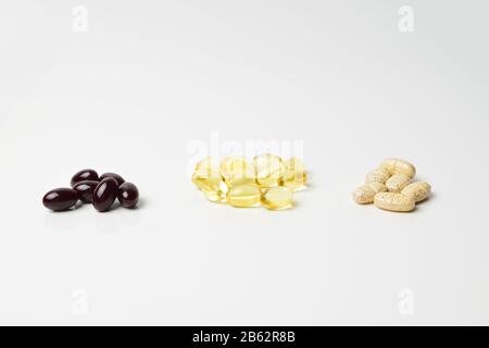 Fischöl, Multivitamine und Astaxanthin-Kapseln in drei Bäuchen. Omega-3 in der Mitte. Weißer Hintergrund. Nahaufnahme. Stockfoto