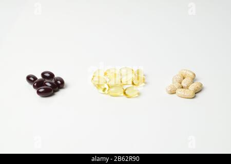 Drei Hündchen Multivitamine, Fischöl und Astaxanthin. Omega-3 in der Mitte. Weißer Hintergrund. Nahaufnahme. Stockfoto