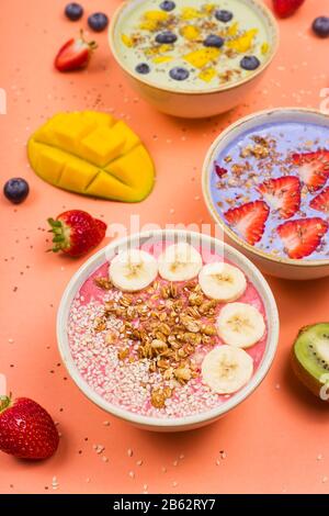 Schöne bunte, gesunde Smoothie-Schüsseln mit Beeren und Superfoods auf hellem Hintergrund. Sommeressen für das Entgiftungskonzept. Stockfoto