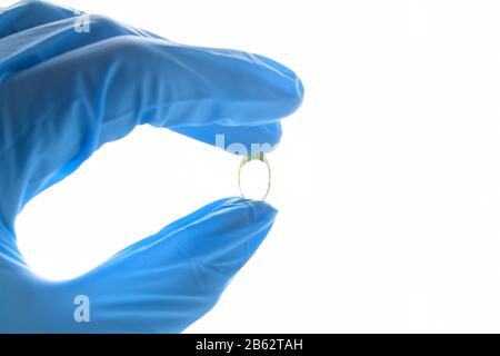 Hand hält eine Fischölpille. Tragen von blauem medizinischem Nitrilhandschuh. Stockfoto