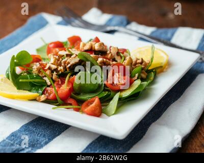 Wintersalat mit Tomaten und gerösteten Walnüssen. Stockfoto