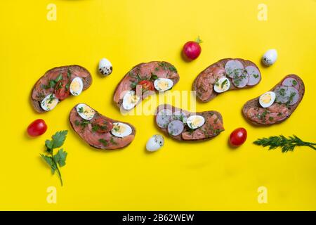 Draufsicht sechs Lachsbrötchen mit Lachs und Wachteleiern auf rotgelbem Hintergrund, flaches Laienfutter Stockfoto