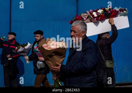 Moskau, Russland. März 2020. Vor dem Internationalen Frauentag in Moskau, Russland, tragen Männer Blumensträuße außerhalb des Rizhsky-Blumenmarktes Stockfoto